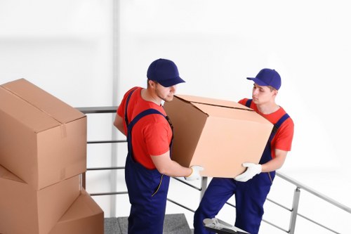 Movers carrying household items from an Islington flat with stairs